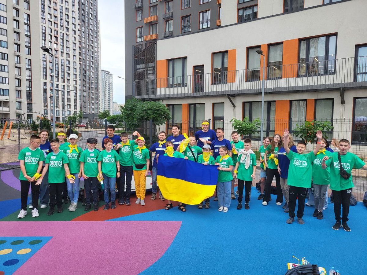 Children and mentors with the Ukrainian flag at the ROBOTICA festival